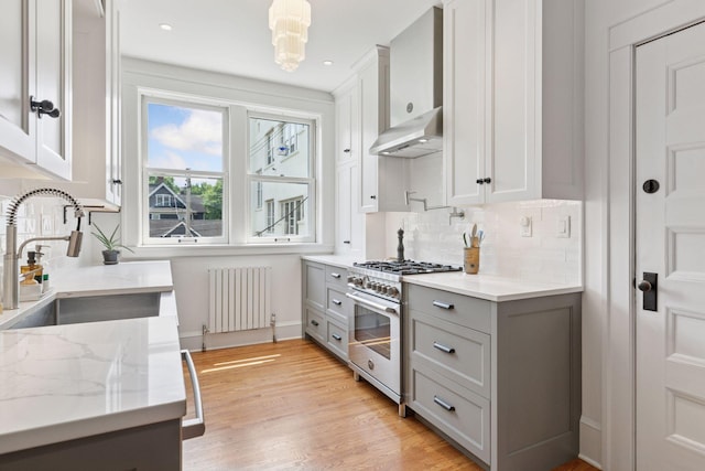 436 Holly Ave Unit 3, Saint Paul, MN 55102 - kitchen featuring radiator heating unit, high end stainless steel range oven, under cabinet range hood, gray cabinets, and backsplash