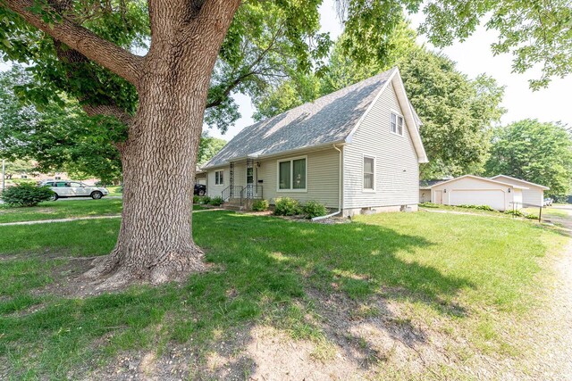 419 Jackson St, Saint Peter, MN 56082 - view of front of property featuring a detached garage, a shingled roof, a front lawn, and an outbuilding