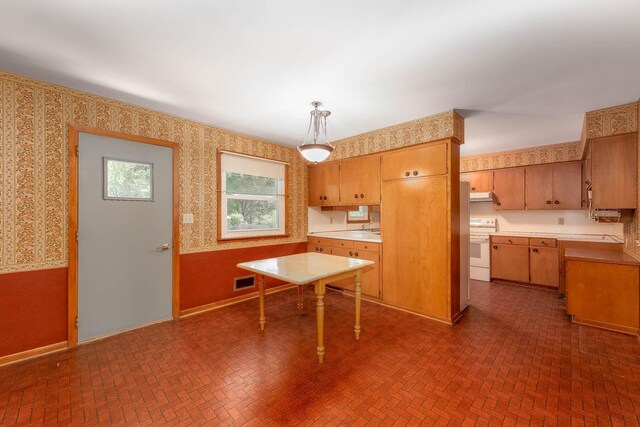 419 Jackson St, Saint Peter, MN 56082 - kitchen with wallpapered walls, white range with electric cooktop, brick patterned floors, light countertops, and under cabinet range hood