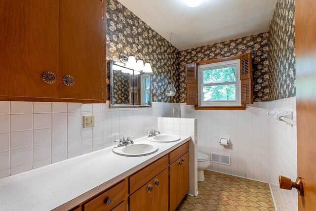 419 Jackson St, Saint Peter, MN 56082 - full bath featuring wallpapered walls, double vanity, a wainscoted wall, and tile walls