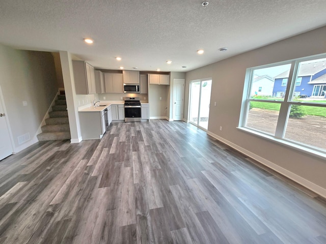 13636 Kaylemore Trl, Rosemount, MN 55068 - unfurnished living room with a textured ceiling, wood finished floors, healthy amount of natural light, recessed lighting, and stairs