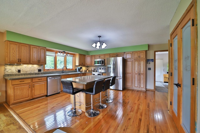 39808 340th Ln, Aitkin, MN 56431 - kitchen with appliances with stainless steel finishes, a chandelier, light wood-style floors, backsplash, and a textured ceiling