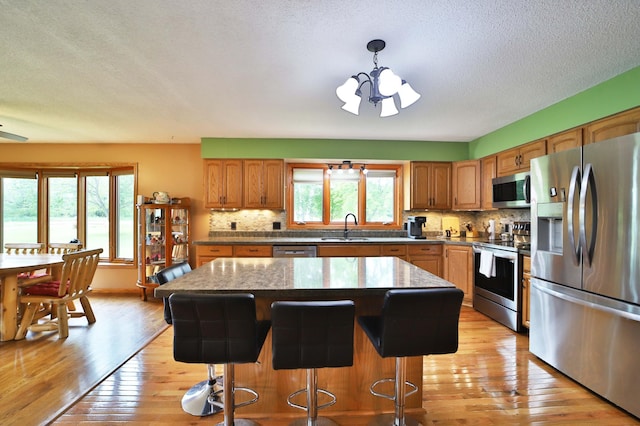 39808 340th Ln, Aitkin, MN 56431 - kitchen with appliances with stainless steel finishes, a chandelier, backsplash, light wood-style floors, and a textured ceiling