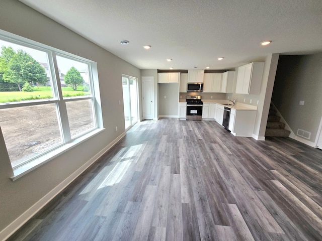 13643 Kaylemore Trl, Rosemount, MN 55068 - unfurnished living room with plenty of natural light, dark wood finished floors, stairs, a textured ceiling, and recessed lighting
