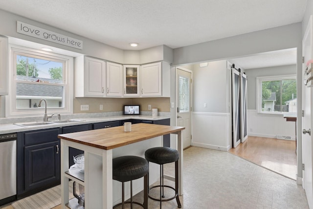 1475 Eldridge Ave E, Maplewood, MN 55109 - kitchen with butcher block countertops, dishwasher, a breakfast bar area, white cabinetry, and a barn door