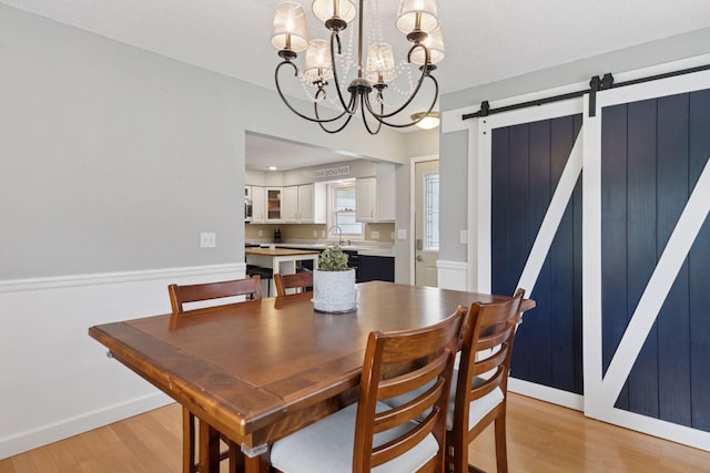 1475 Eldridge Ave E, Maplewood, MN 55109 - dining space featuring a barn door, a chandelier, and light wood-style flooring