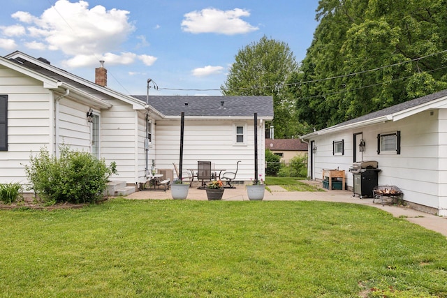 1475 Eldridge Ave E, Maplewood, MN 55109 - back of property featuring a patio, a yard, a chimney, and roof with shingles