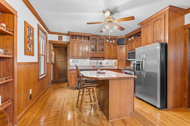 20930 St Francis Blvd NW, Nowthen, MN 55303 - kitchen with stainless steel appliances, ceiling fan, brown cabinetry, light wood-type flooring, and a center island