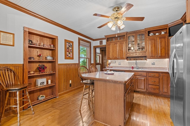 20930 St Francis Blvd NW, Nowthen, MN 55303 - kitchen with freestanding refrigerator, a wainscoted wall, brown cabinetry, light countertops, and a breakfast bar