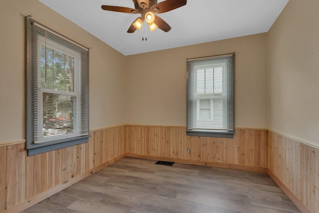 200 27th Ave N, Saint Cloud, MN 56303 - unfurnished room with a wainscoted wall, wood walls, wood finished floors, and ceiling fan