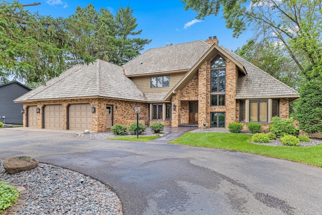 10810 Mississippi Blvd NW, Coon Rapids, MN 55433 - view of front of property featuring asphalt driveway, an attached garage, brick siding, a chimney, and a front lawn