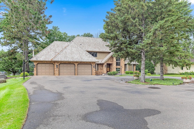 10810 Mississippi Blvd NW, Coon Rapids, MN 55433 - view of front facade featuring a garage, asphalt driveway, brick siding, and a front lawn
