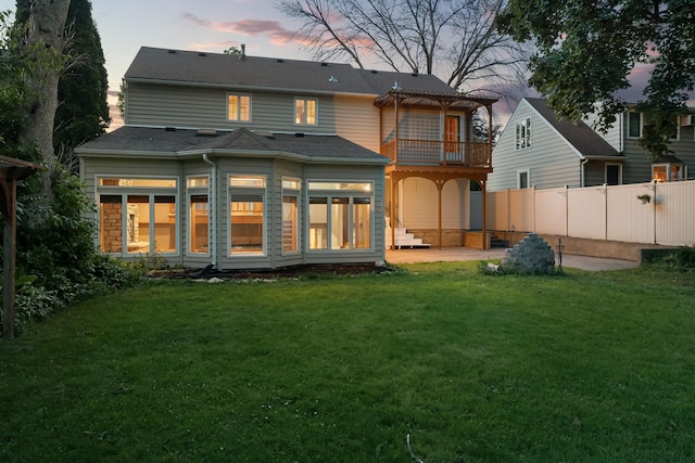 1218 4th Ave SE, Austin, MN 55912 - back of house at dusk featuring a balcony and a patio
