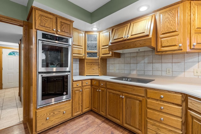 1218 4th Ave SE, Austin, MN 55912 - kitchen with double oven, black electric stovetop, light countertops, backsplash, and brown cabinets