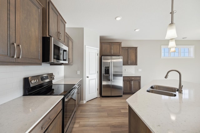 8007 Walnut Ln, Corcoran, MN 55340 - kitchen with appliances with stainless steel finishes, tasteful backsplash, light wood-style flooring, hanging light fixtures, and light stone counters