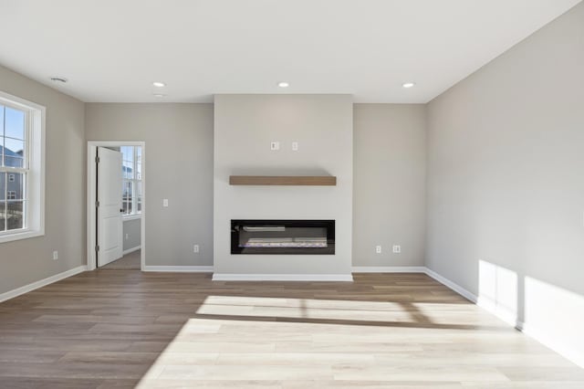 8007 Walnut Ln, Corcoran, MN 55340 - unfurnished living room with wood finished floors, a glass covered fireplace, and recessed lighting