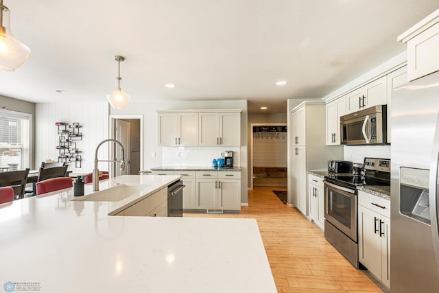 5480 Tanner Ave S, Fargo, ND 58104 - kitchen with appliances with stainless steel finishes, light wood-style floors, backsplash, decorative light fixtures, and recessed lighting