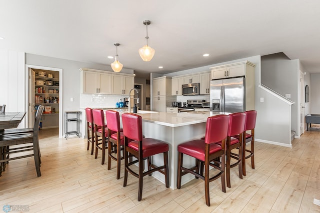 5480 Tanner Ave S, Fargo, ND 58104 - kitchen featuring stainless steel appliances, light countertops, light wood-style floors, a kitchen bar, and recessed lighting