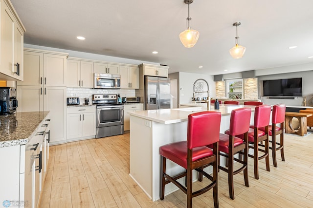 5480 Tanner Ave S, Fargo, ND 58104 - kitchen featuring appliances with stainless steel finishes, light wood-style flooring, tasteful backsplash, a kitchen bar, and recessed lighting