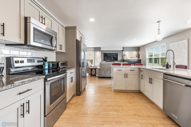 5480 Tanner Ave S, Fargo, ND 58104 - kitchen with appliances with stainless steel finishes, open floor plan, light wood-style flooring, recessed lighting, and backsplash
