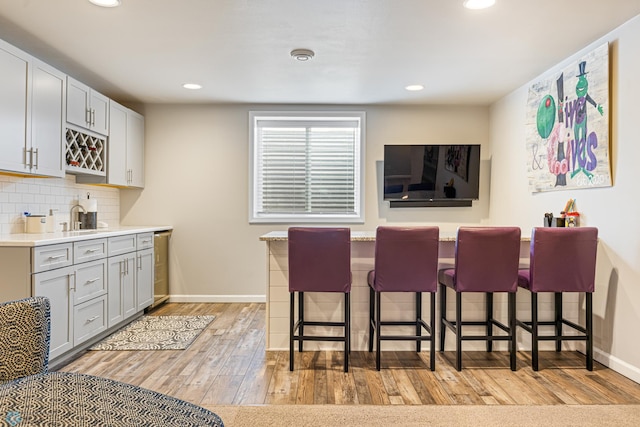 5480 Tanner Ave S, Fargo, ND 58104 - kitchen featuring a breakfast bar, light wood-style flooring, recessed lighting, decorative backsplash, and light countertops
