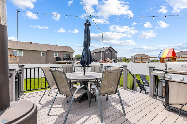 5480 Tanner Ave S, Fargo, ND 58104 - wooden deck featuring outdoor dining space, area for grilling, a playground, and a residential view