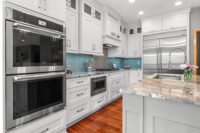2334 Veterans Memorial Blvd NW, Andover, MN 55304 - kitchen featuring built in appliances, backsplash, white cabinets, glass insert cabinets, and dark wood finished floors