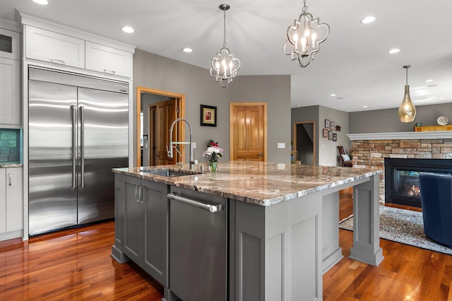 2334 Veterans Memorial Blvd NW, Andover, MN 55304 - kitchen featuring appliances with stainless steel finishes, wood finished floors, light stone counters, a center island with sink, and recessed lighting
