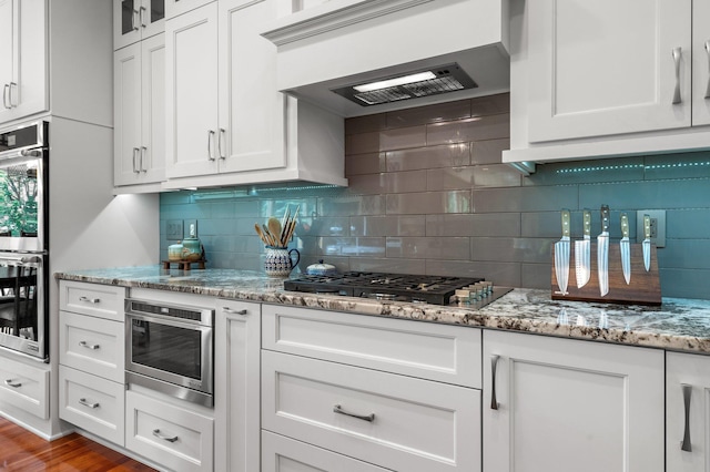2334 Veterans Memorial Blvd NW, Andover, MN 55304 - kitchen with stainless steel appliances, ventilation hood, white cabinets, and backsplash
