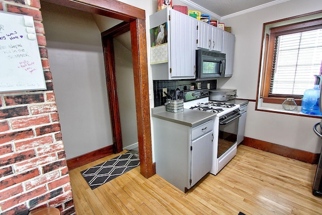 1936 5th St, Red Wing, MN 55066 - kitchen featuring black microwave, white gas stove, ornamental molding, light wood finished floors, and tasteful backsplash
