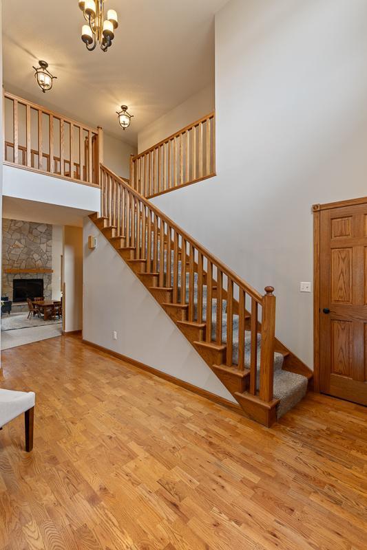 18505 210th Ave NE, Paynesville, MN 56362 - staircase featuring wood finished floors, a chandelier, a stone fireplace, and a towering ceiling