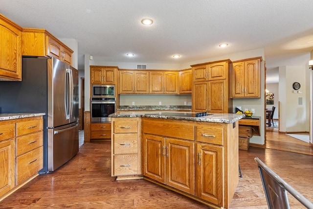 18505 210th Ave NE, Paynesville, MN 56362 - kitchen with appliances with stainless steel finishes, dark wood-type flooring, a kitchen island, brown cabinets, and recessed lighting
