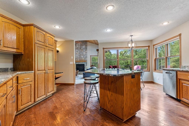 18505 210th Ave NE, Paynesville, MN 56362 - kitchen with dishwasher, dark wood-style floors, a textured ceiling, a stone fireplace, and brown cabinetry