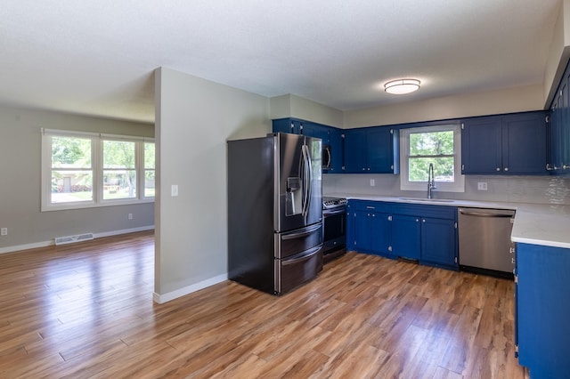 1744 Oak Rd, Saint Cloud, MN 56303 - kitchen featuring appliances with stainless steel finishes, blue cabinetry, light wood finished floors, and tasteful backsplash
