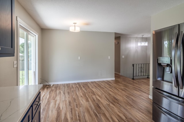 1744 Oak Rd, Saint Cloud, MN 56303 - unfurnished dining area featuring light wood-style floors, a chandelier, and a textured ceiling