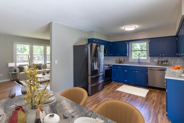 1744 Oak Rd, Saint Cloud, MN 56303 - kitchen featuring appliances with stainless steel finishes, blue cabinetry, light wood-type flooring, light countertops, and backsplash