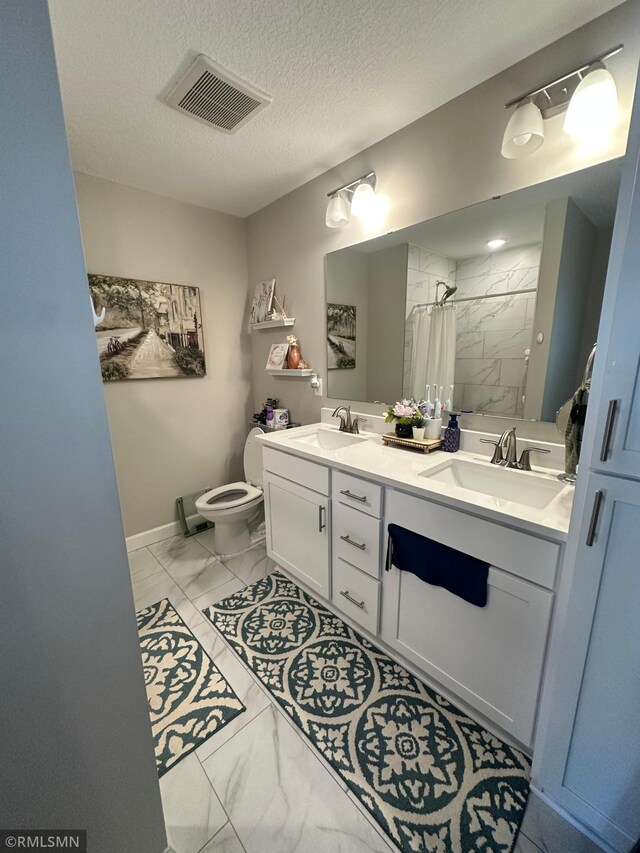 1004 Triumph Trl NE, Isanti, MN 55040 - bathroom featuring marble finish floors, a tile shower, double vanity, and a textured ceiling