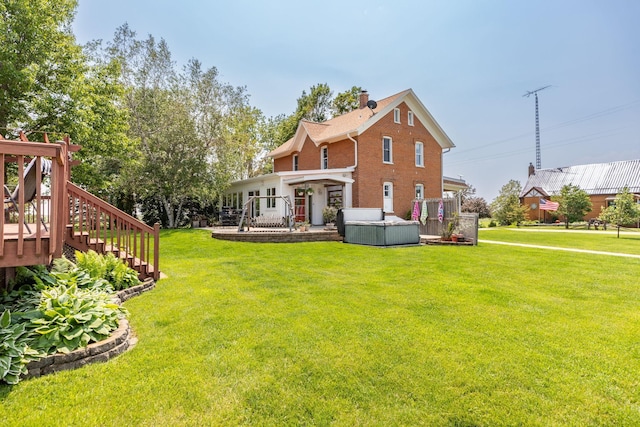 10706 65th Ave SE, Stewartville, MN 55976 - back of house featuring a hot tub, a yard, a chimney, and brick siding