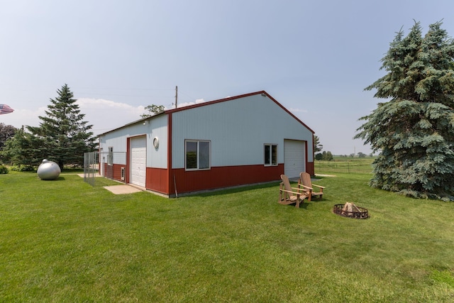10706 65th Ave SE, Stewartville, MN 55976 - back of house featuring an outdoor fire pit, a detached garage, a lawn, and an outdoor structure