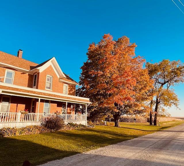 10706 65th Ave SE, Stewartville, MN 55976 - view of front of home featuring a porch, a front lawn, brick siding, and a chimney