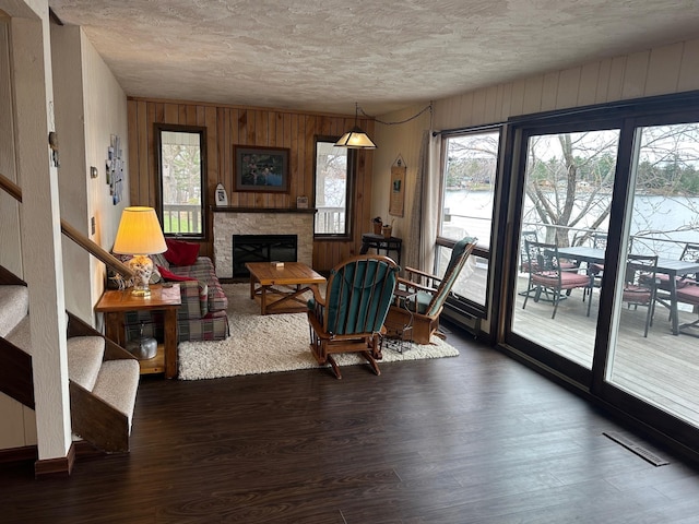 34447 Blue Acres Ln, Crosslake, MN 56442 - living room featuring a textured ceiling, a fireplace, wood finished floors, wooden walls, and stairs