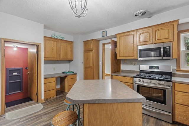 613 Oak St, Farmington, MN 55024 - kitchen with appliances with stainless steel finishes, dark wood-style flooring, a textured ceiling, a kitchen breakfast bar, and a kitchen island