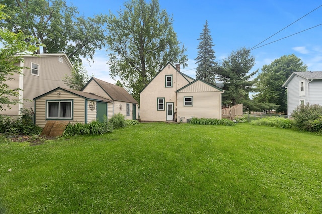 613 Oak St, Farmington, MN 55024 - back of property with a lawn, a chimney, a storage shed, and stucco siding