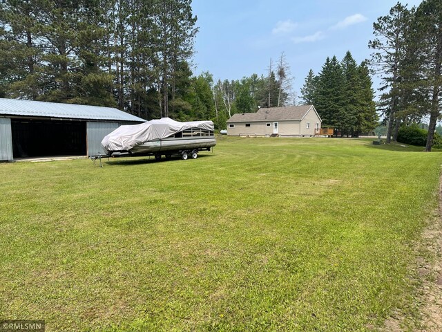 21507 County Road 560, Goodland Twp, MN 55742 - view of grassy yard featuring a pole building, an outbuilding, and view of wooded area