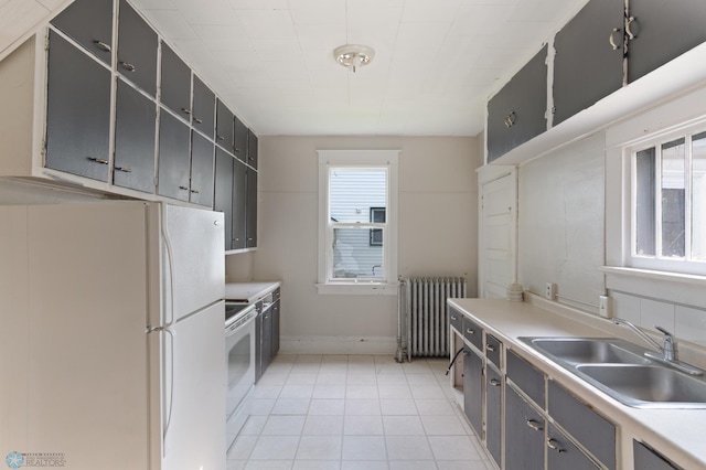 824 9th St N, Fargo, ND 58102 - kitchen with radiator, white appliances, light tile patterned flooring, gray cabinetry, and light countertops