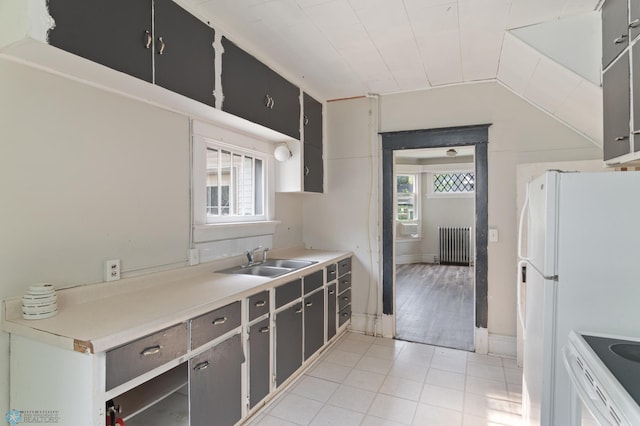 824 9th St N, Fargo, ND 58102 - kitchen with radiator, white appliances, light tile patterned floors, light countertops, and lofted ceiling