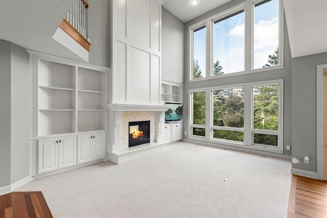 10701 Sonoma Rdg, Eden Prairie, MN 55347 - unfurnished living room with a fireplace, plenty of natural light, a towering ceiling, light wood-style flooring, and built in shelves