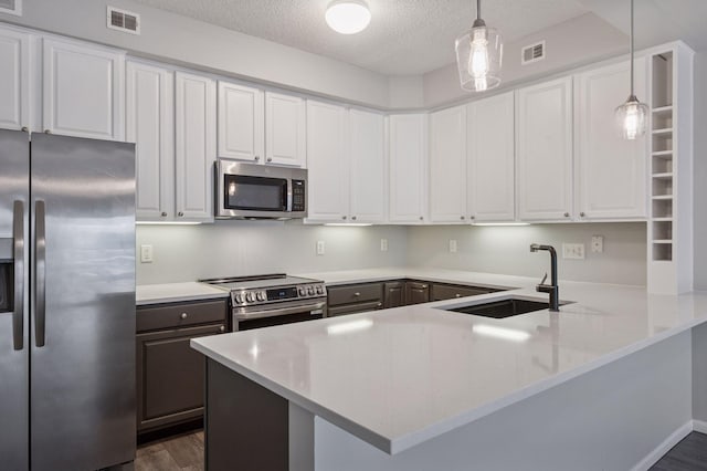 7601 Garfield Ave Unit 103, Richfield, MN 55423 - kitchen featuring appliances with stainless steel finishes, a peninsula, dark wood-style floors, white cabinets, and a textured ceiling