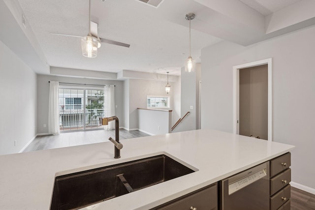 7601 Garfield Ave Unit 103, Richfield, MN 55423 - kitchen with stainless steel dishwasher, open floor plan, light countertops, decorative light fixtures, and wood finished floors