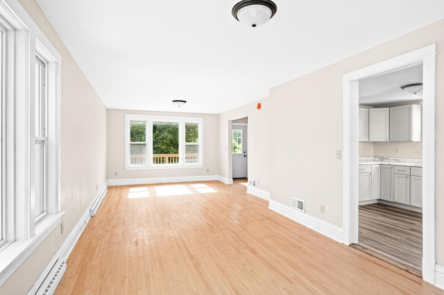 808 6th Ave E, Duluth, MN 55805 - unfurnished room featuring light wood finished floors and a baseboard heating unit